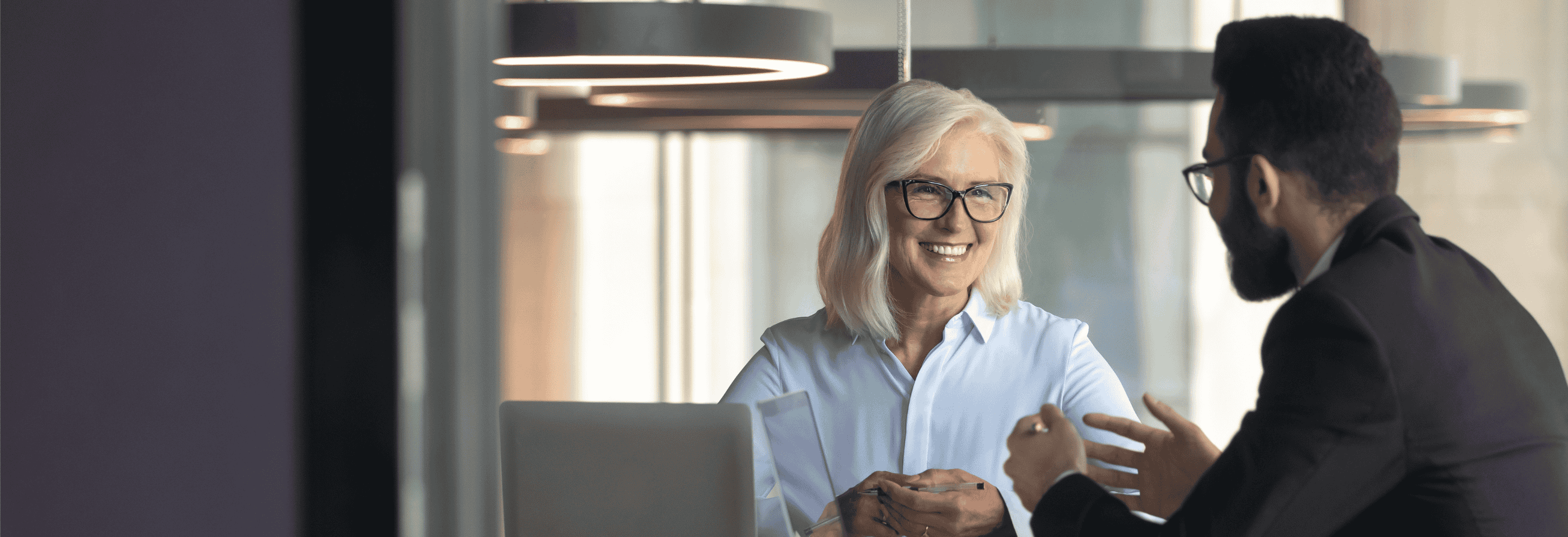 Smilende kvinnelig senior i samtale med mannlig kollega