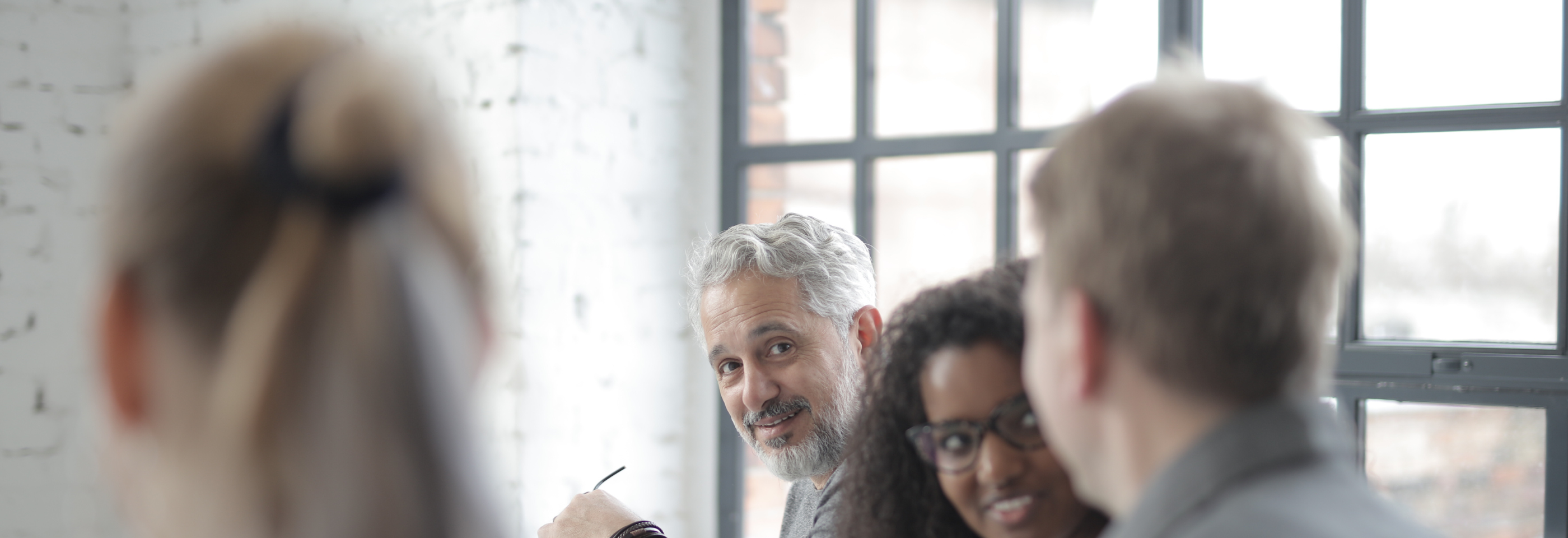 Gruppe kolleger som smiler og snakker sammen i et lyst møterom