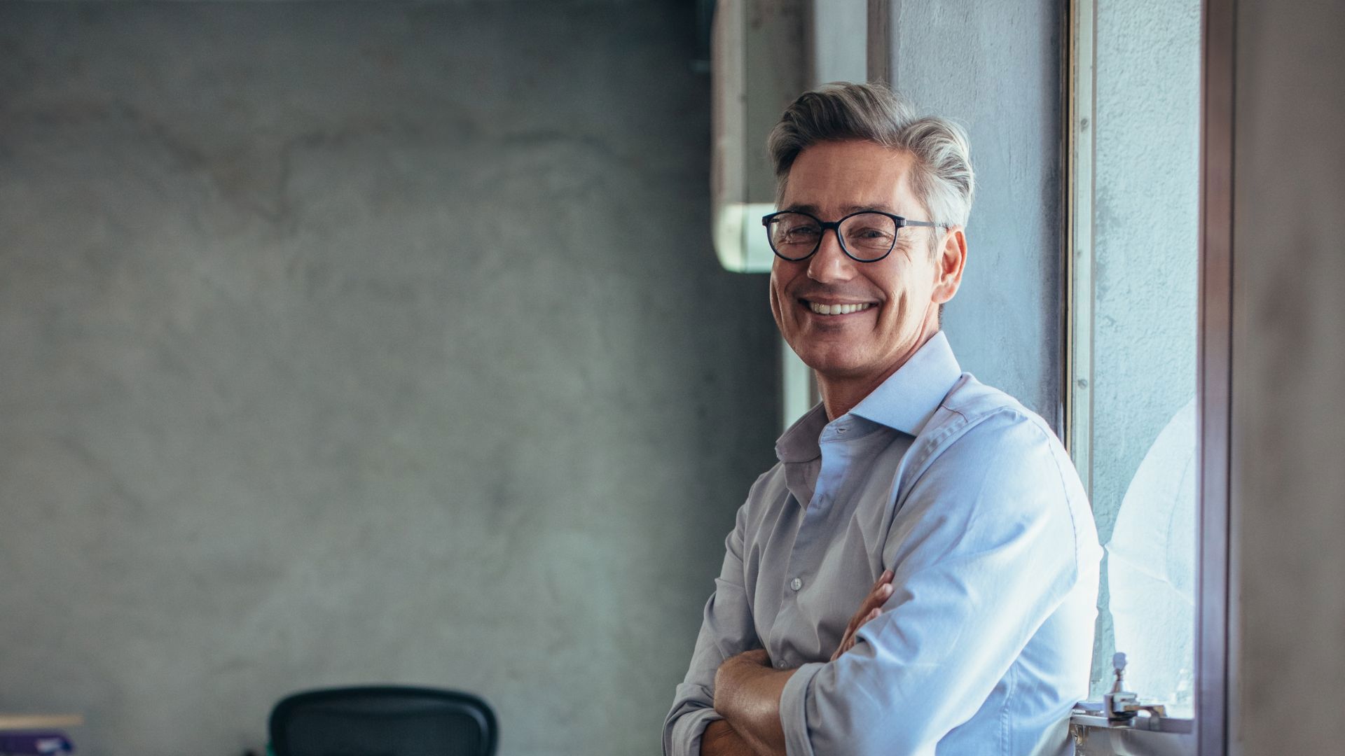 Selvsikker forretningsmann som smiler på kontoret, og representerer lederskap, positivitet