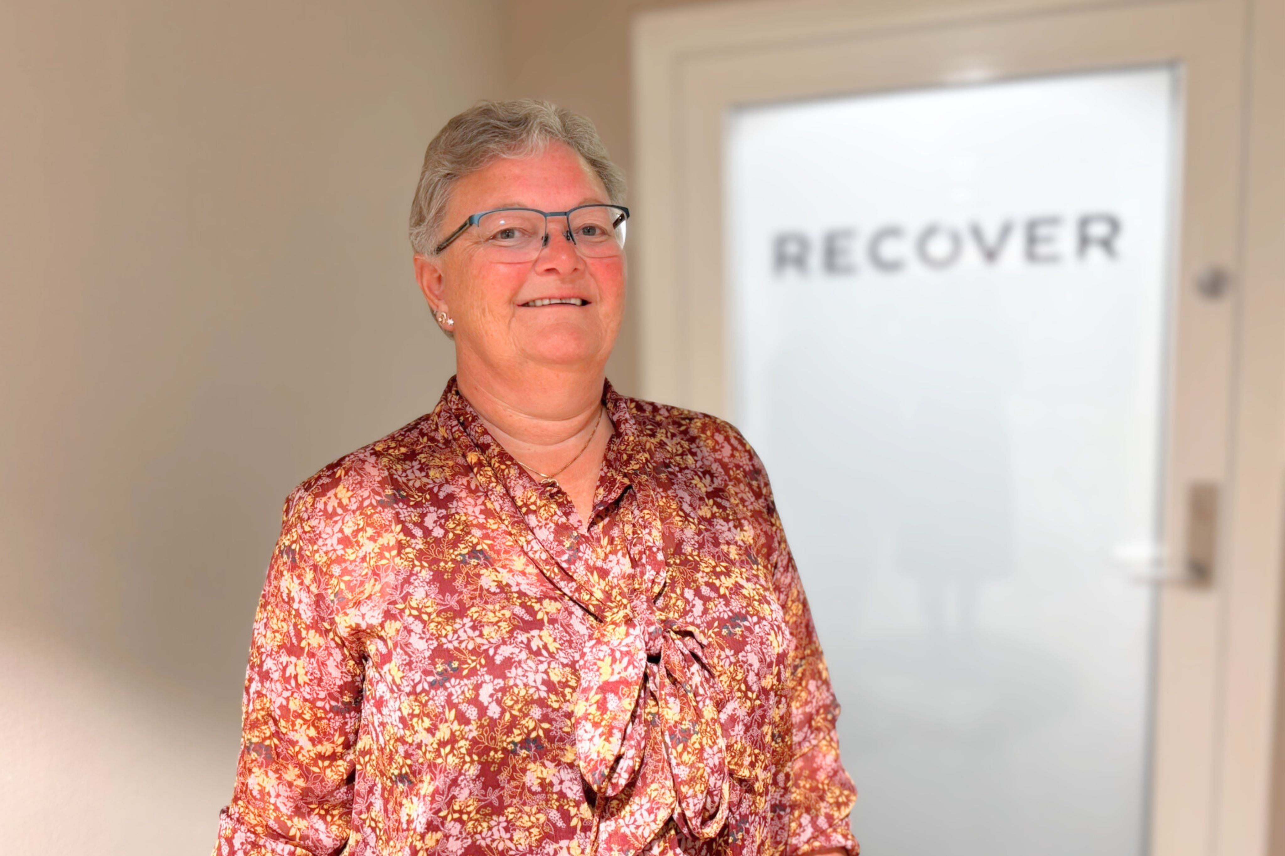 Eldre kvinnelig medarbeider foran arbeidsgivers inngangsdør